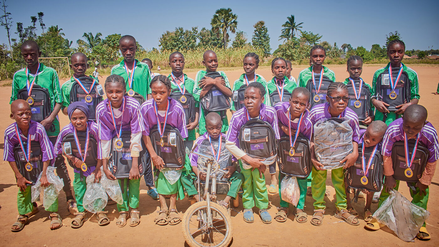 A large group of children in sportswear pose with medals after a football game.