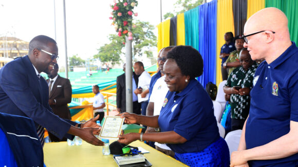 A woman presents a document to a man at an event about disability inclusion in Tanzania.