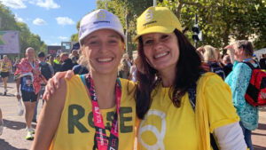 Rose smiles in her Sightsavers vest, next to one of Sightsavers' staff members.