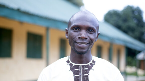 Teacher Zachariah smiles at the camera.