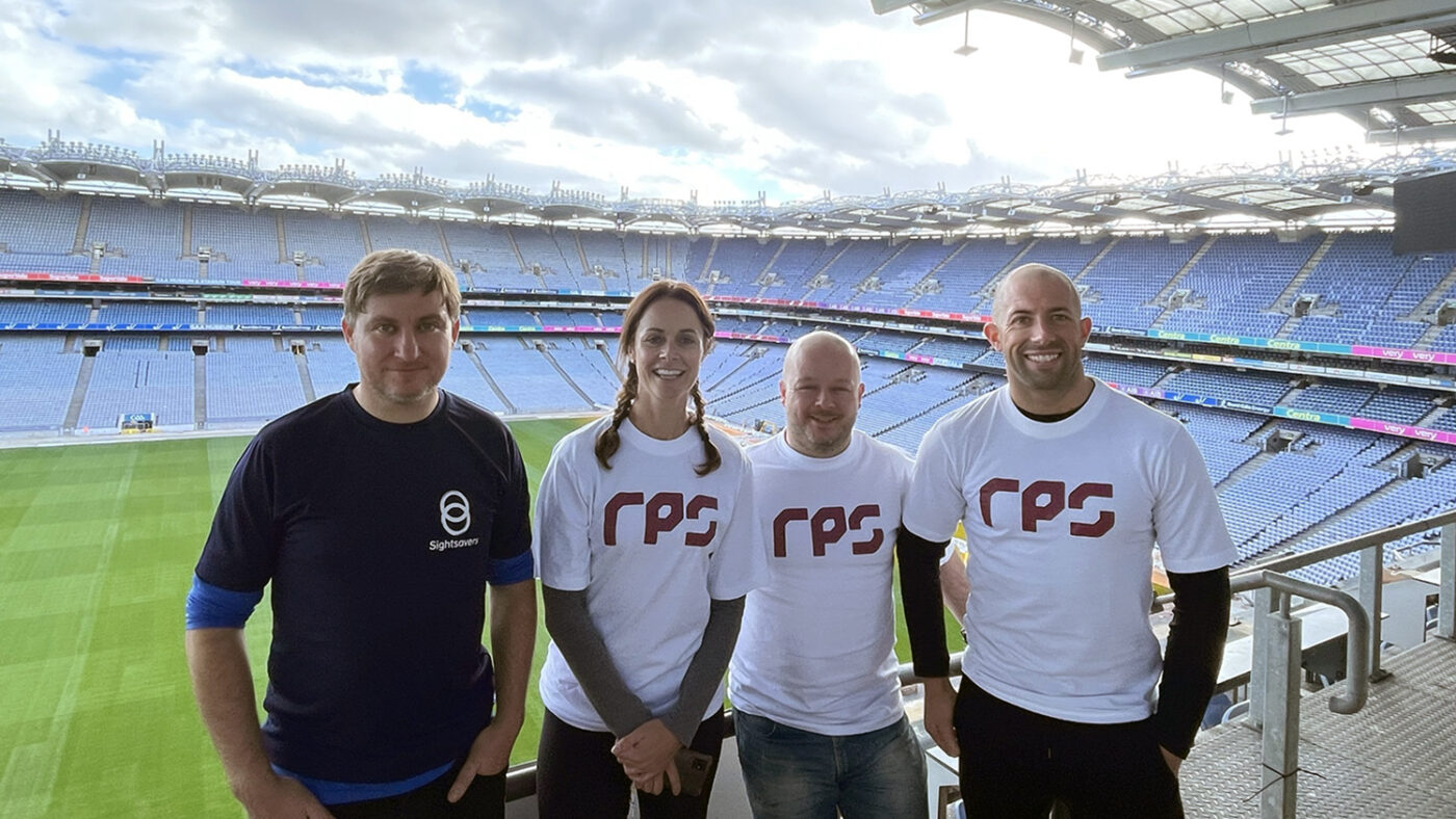 A group of four men and women pose at Croke Park in Dublin. Three members of the group are wearing RPS t-shirts.