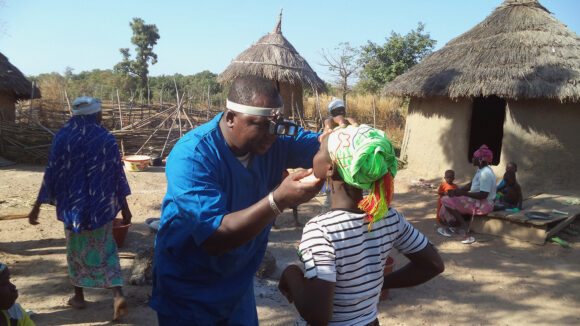 An eye doctor checks a woman's eyes for signs of trachoma.