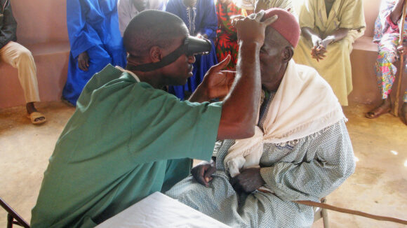An eye health worker checks a man's eyes for signs of trachoma.