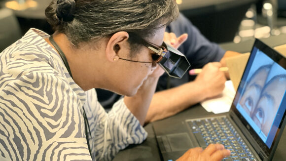 An eye health worker looks at images on a laptop during a trachoma training session.