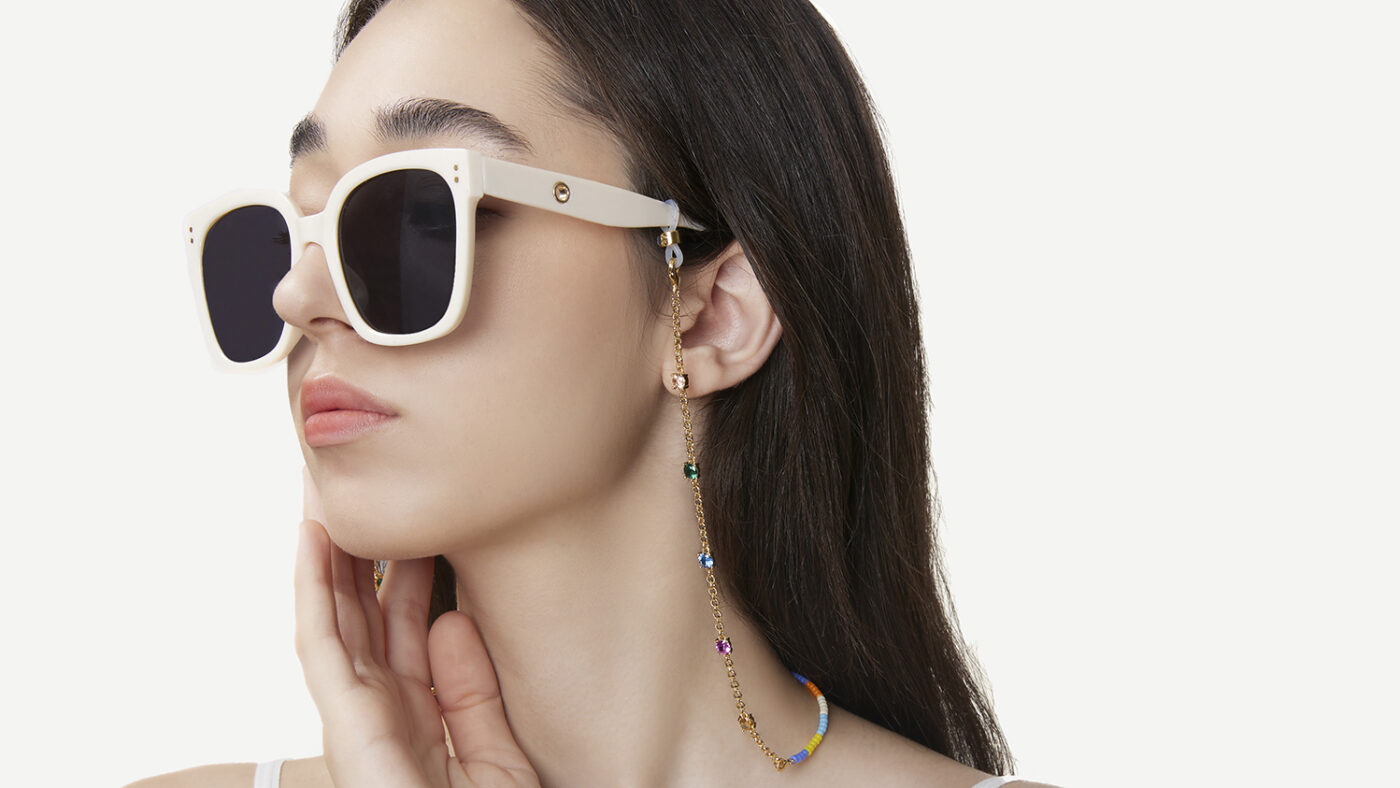 A model wears a pair of sunglasses with a chain by Frida and Florence.