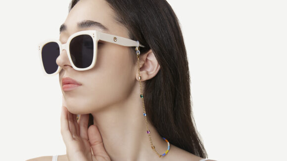 A model wears a pair of sunglasses with a chain by Frida and Florence.