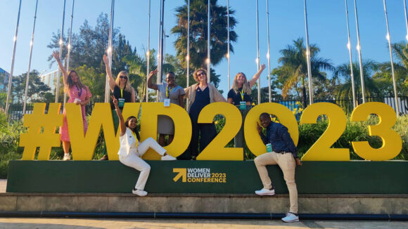 Sightsavers staff stand in front of yellow lettering saying '#WD2023'.