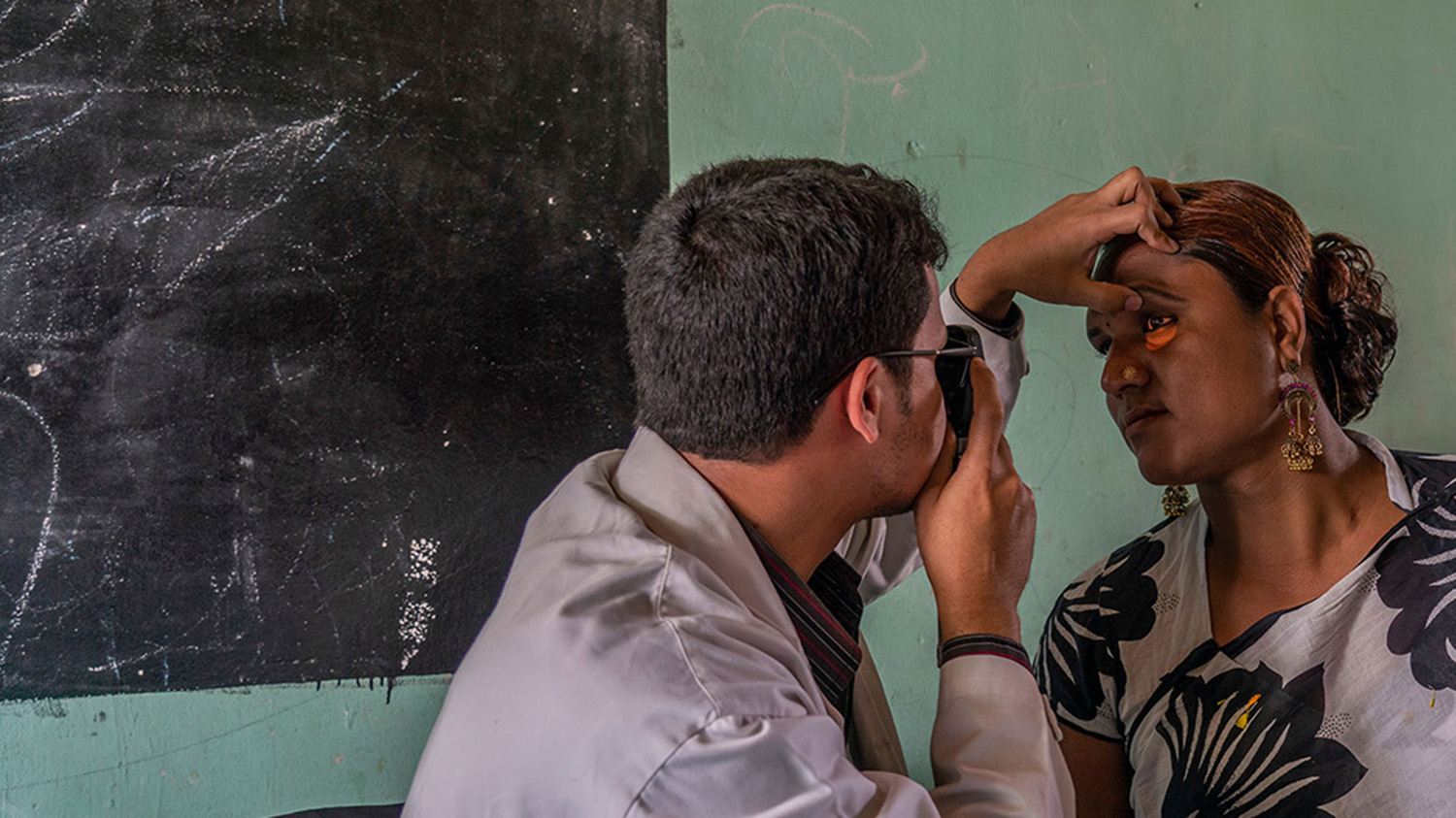 An eye health worker shines a torch into Bristy's eye during an eye exam.