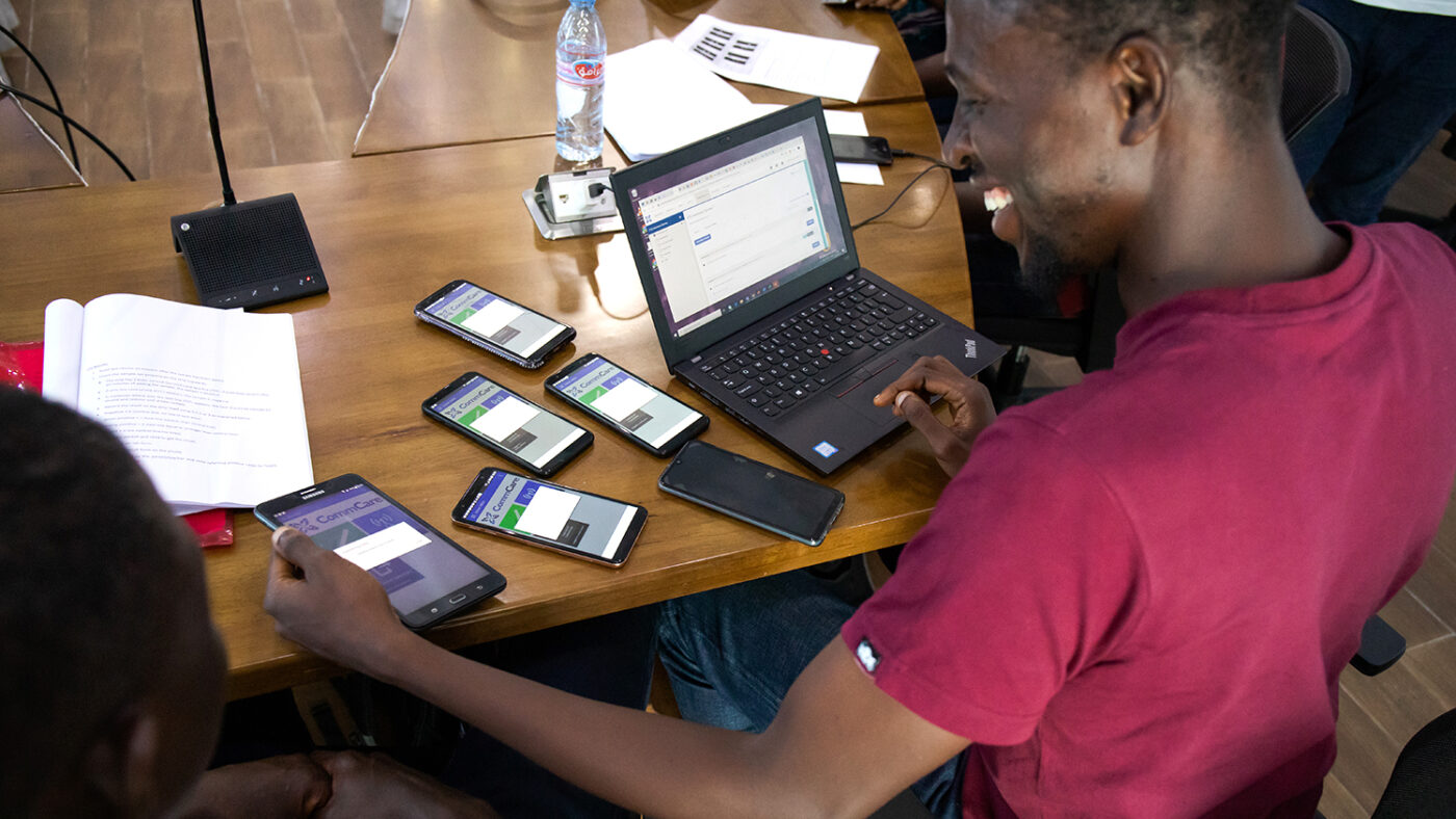 Data gatherer Abakar in Liberia sits at a desk with a computer and several mobile phones.