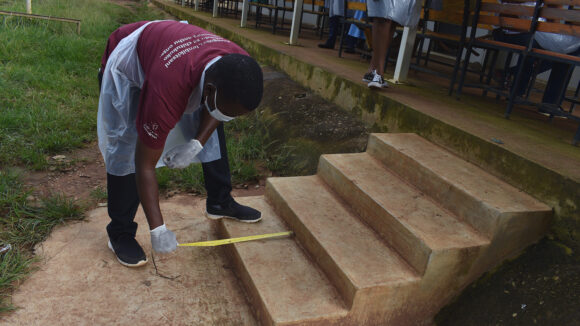 A man measures the depth of some steps during an accessibility audit.