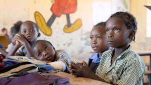 Students at an inclusive school in Zambia sit around a desk.