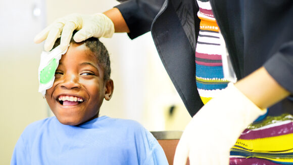A young girl smiles broadly as her bandage is removed following cataract surgery.