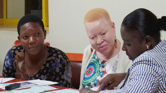 Three women discuss gender-based violence at a workshop in Uganda.