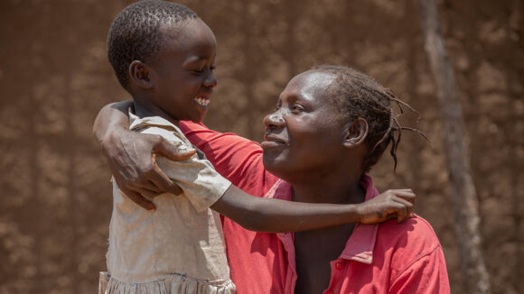 A mother and her young daughter hug and smile.