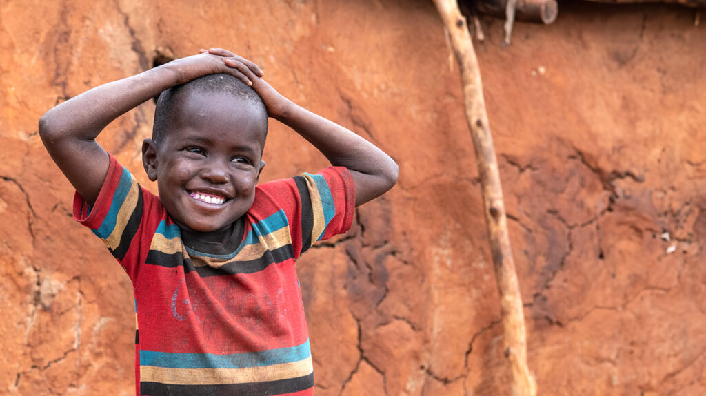 Lanoi stands outside and smiles with her hands on top of her head. She looks off to the right.