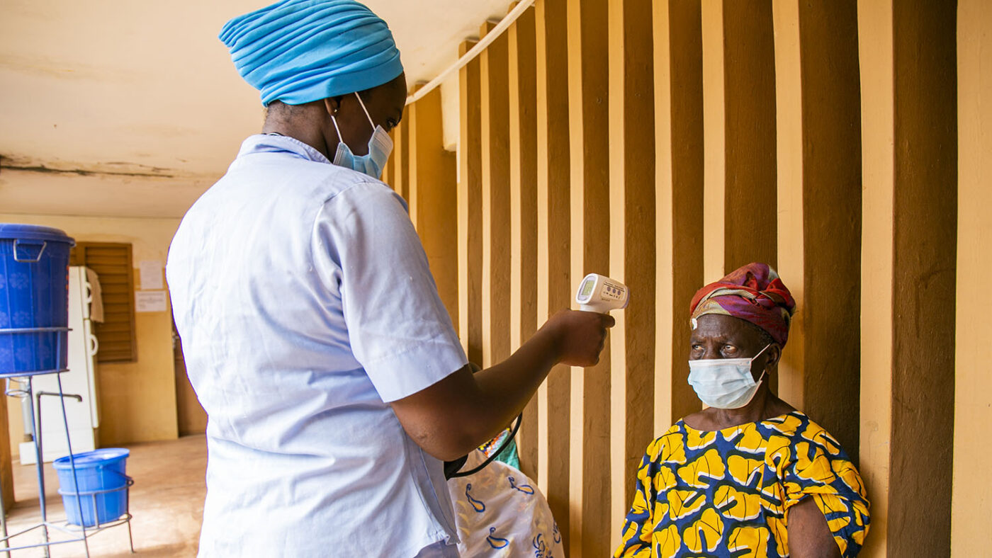 A nurse wearing PPE takes the temperature of a patient at an eye clinic.