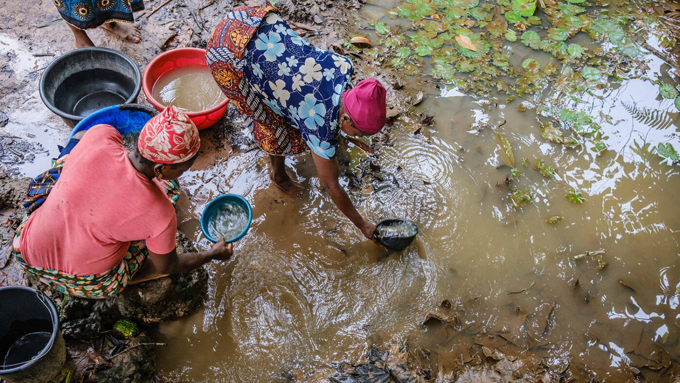 Two women collect water from a river in Nigeria.
