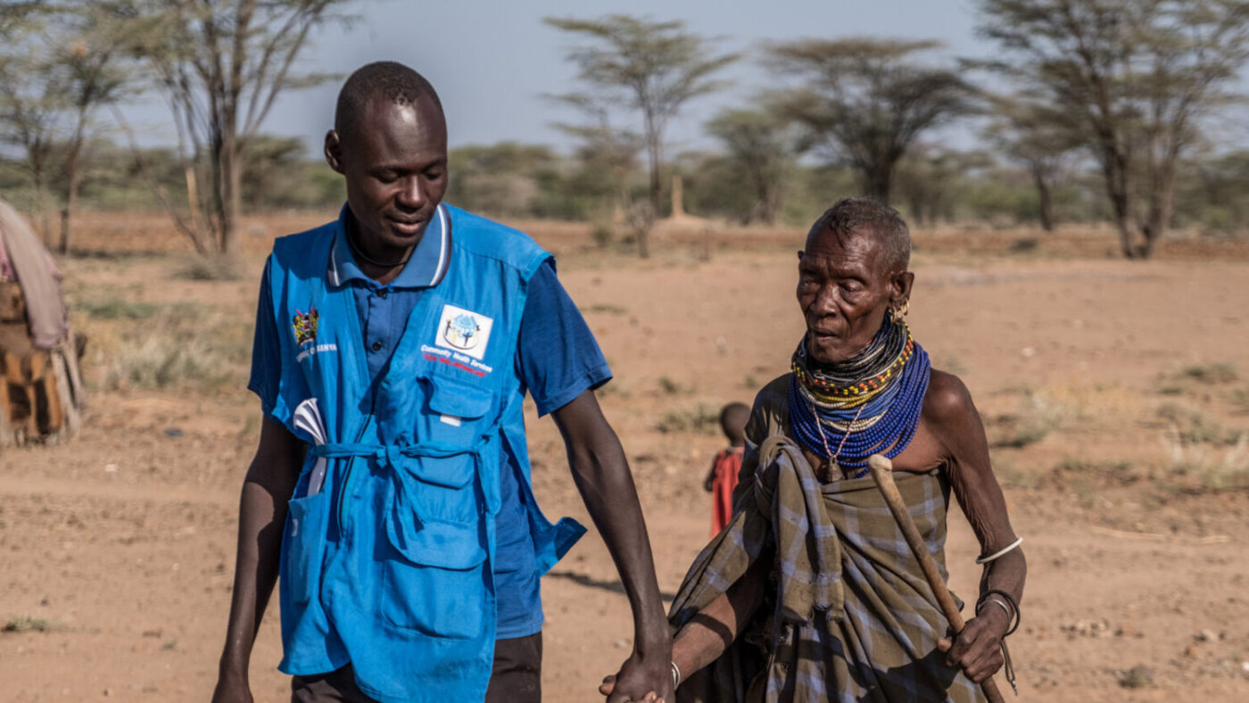 Community volunteer taking trachoma patient Akai to go to her surgery