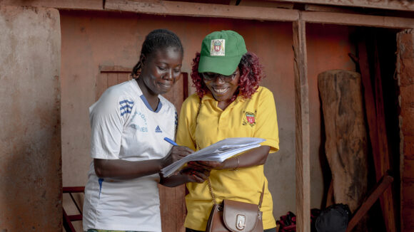 Carine, a council data collector, speaks to Godjon outside her home in Nkoteng, Cameroon.