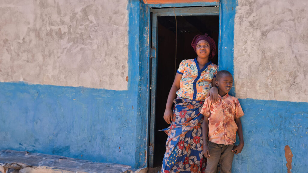 Joseph stadning with his aunt, Rudia in the doorway of their home