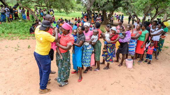A line of people waiting to have their eyes checked by the male nurse