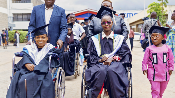 IT Bridge Academy students wearing traditional graduation caps and gowns.