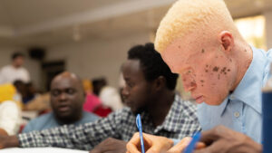 A man with albinism takes notes during a workshop on political participation in Sierra Leone.