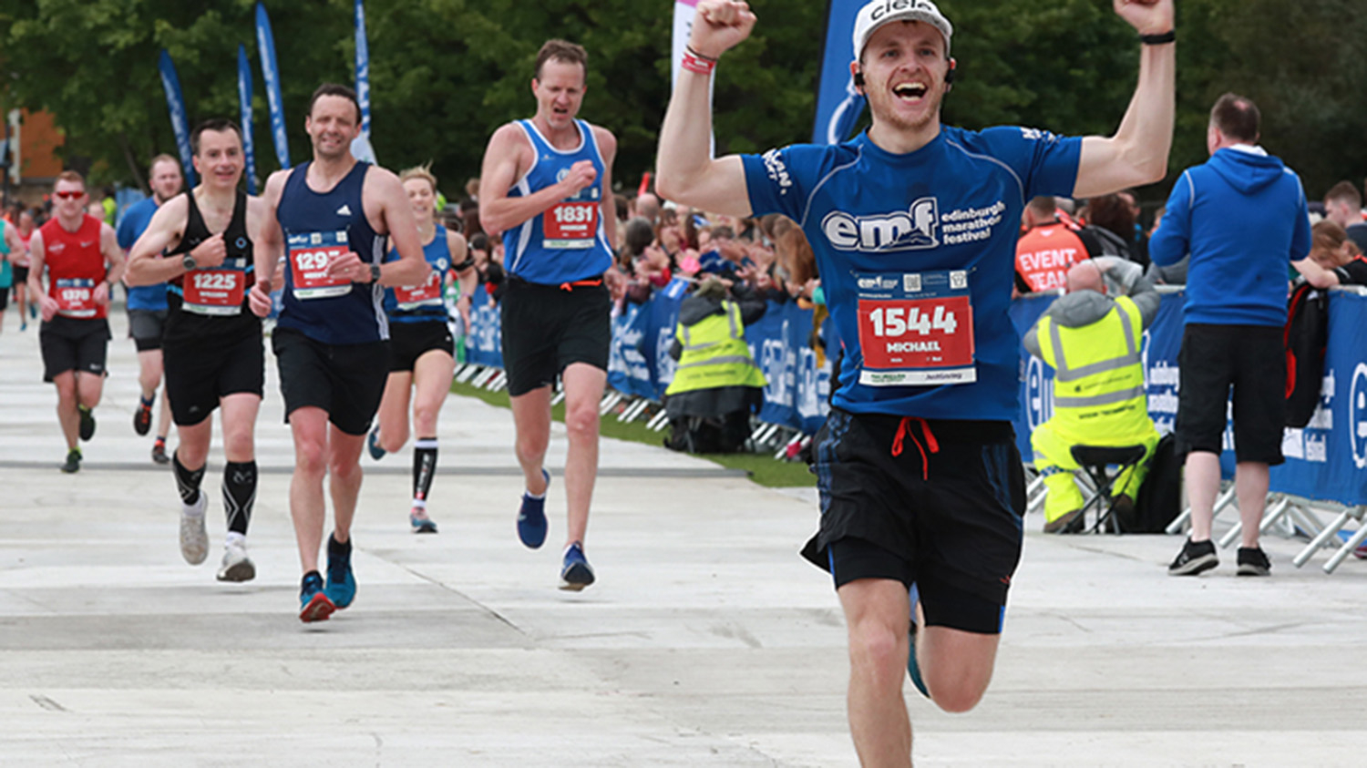 A man cheers and raises his arms as he reaches the finish line of the Edinburgh Marathon.