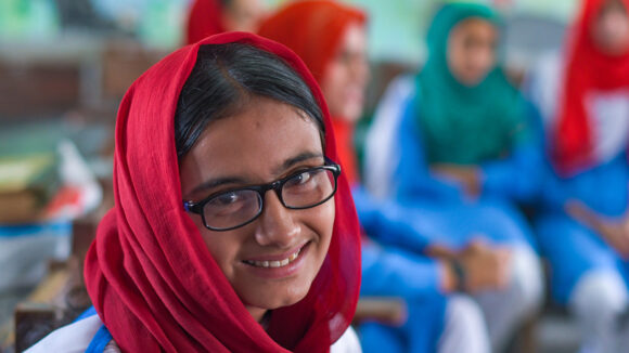 12-year-old Fiza smiles after receiving glasses through an eye test at her school.