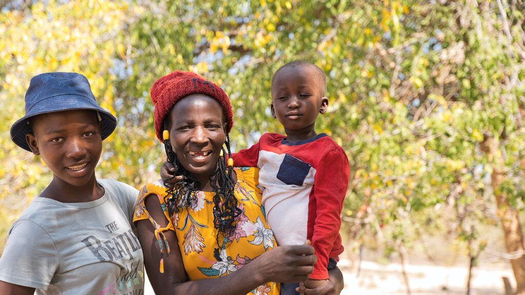 Maria holds a young child while standing next to a teenage girl.