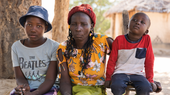 Maria sits with two of her children outside.