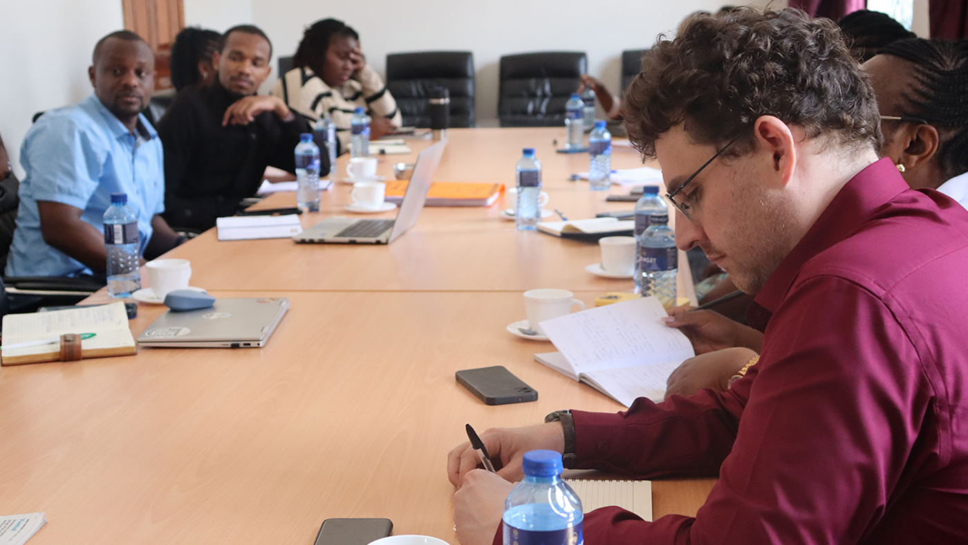 A group of people meet around a large table inside a corporate boardroom.