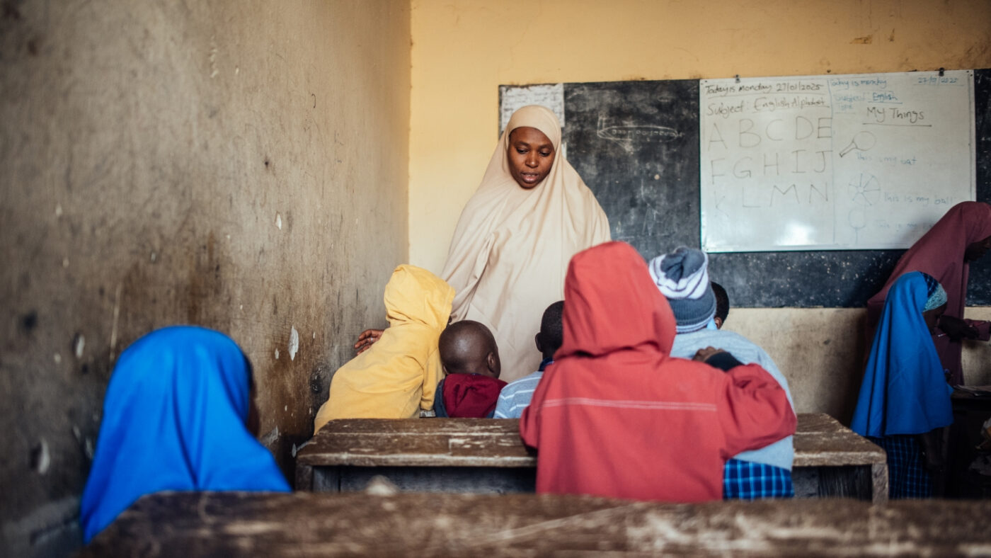 Miss Imam teaches at the front of a classroom in Nigeria.