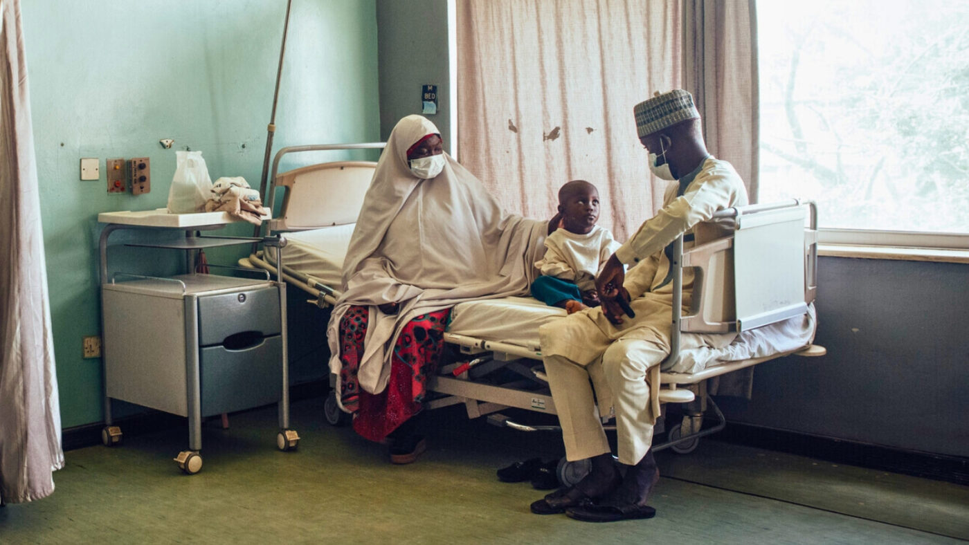 Muhammad sits on a hospital bed between his father and grandmother.