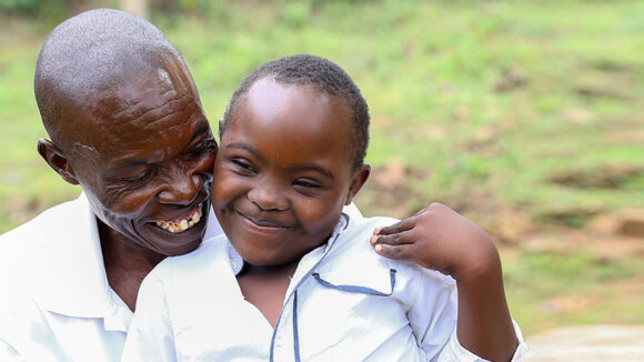 Absalom hugs his daughter Irene, who has a disability. They're both smiling.