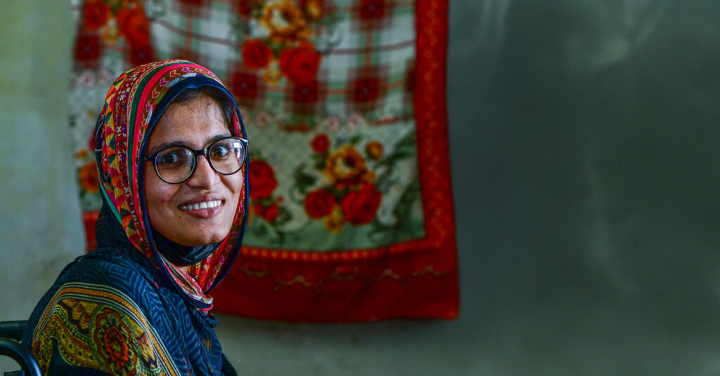 Aasiya wearing a pair of glasses. She has a colourful scarf over her hair.