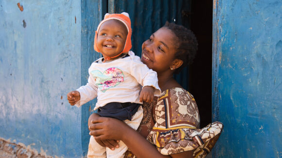 Rudi holds her 11-month-old toddler Ebenezeri. They're both smiling.