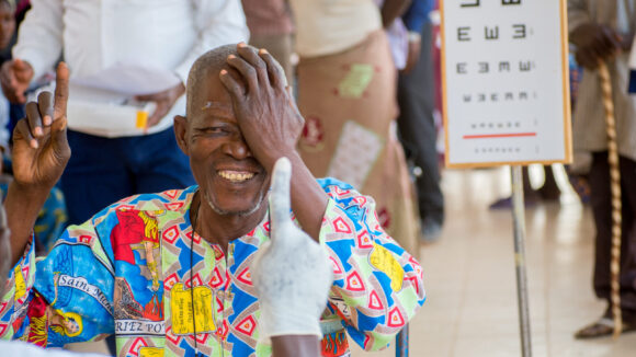 A man cover one eye with his hand during an eye test.