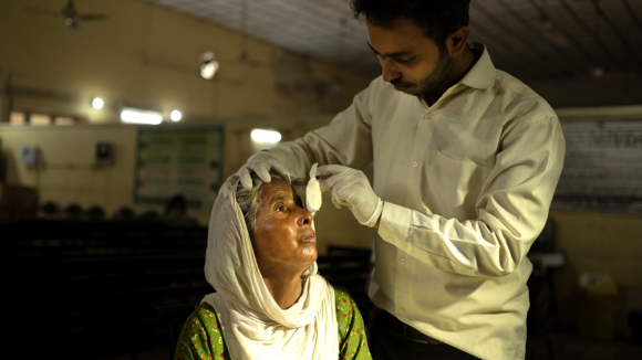 A man is removing a woman's eye bandages.