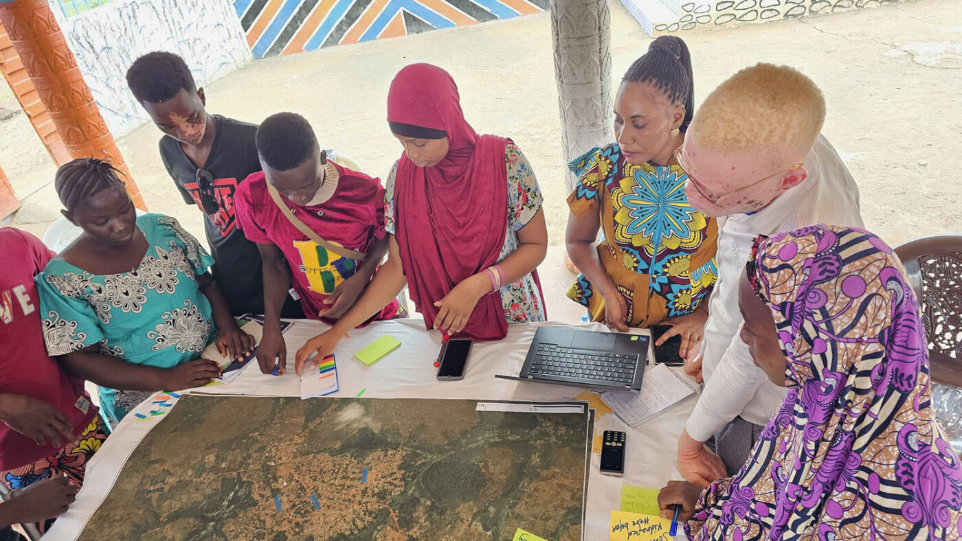 A group of young people gathers around a map.