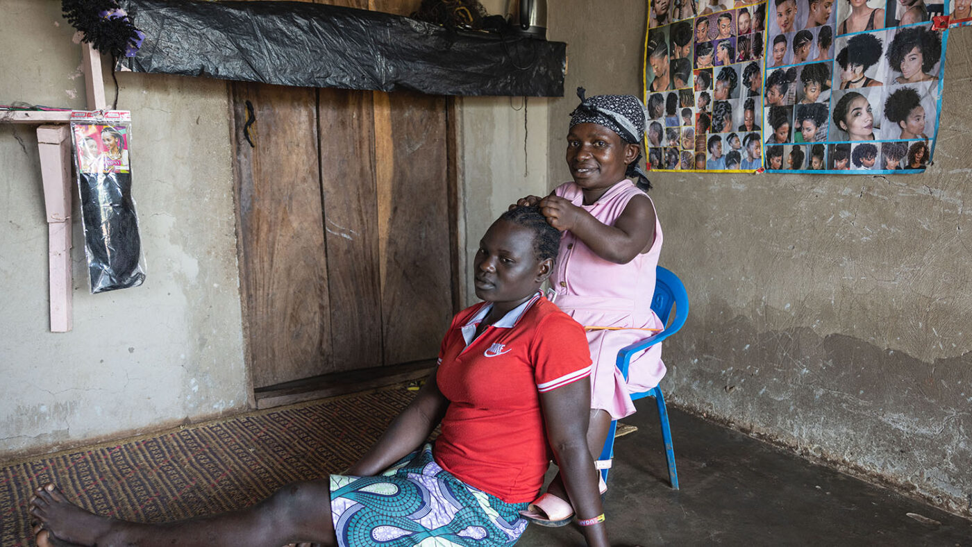 Lydia, who is a person of short stature, braids a female customer's hair.