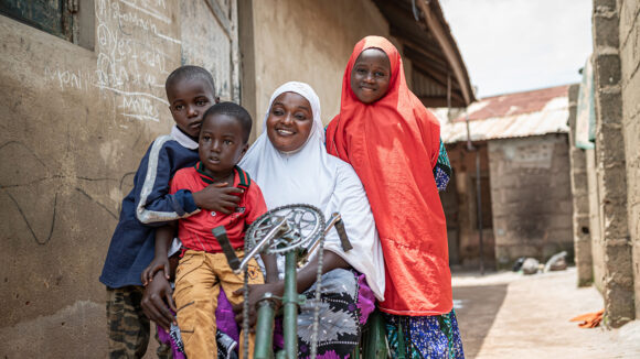 A woman using a mobility scooter is surrounded by her three children.