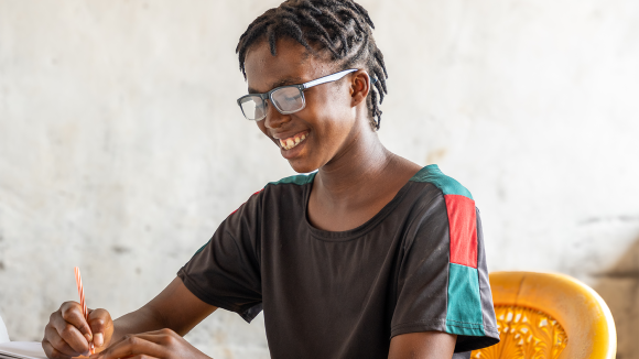 Photo of Lydia smiling whilst writing in a book