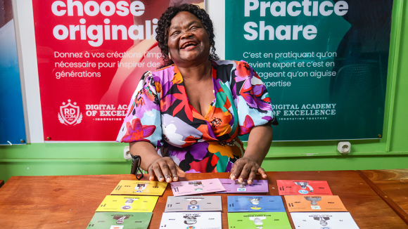 A woman smiles, sitting behind a desk with colourful cards.