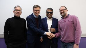 Four men wearing office attire shake hands.