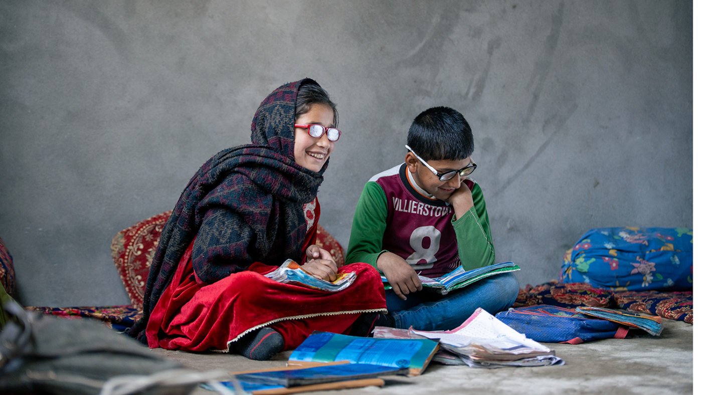 Saira and Zayn sat down smiling and laughing whilst reading books.