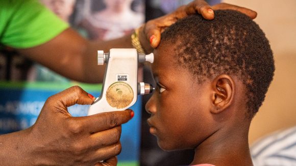 A young girl looks into a medical device during an eye test.